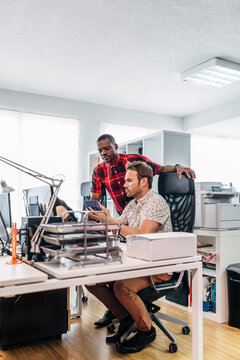Coworkers collaborating on smartphone in modern office