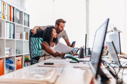 Coworkers reviewing documents and data at modern office desk