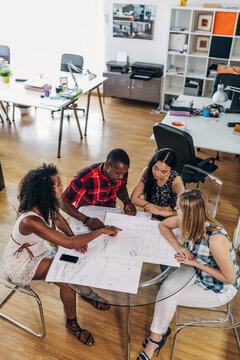 Diverse team reviewing architectural blueprint in modern office
