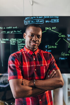 Confident teacher in classroom with blackboard and notes