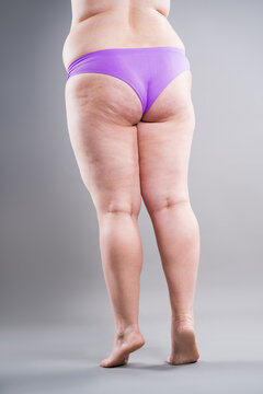 Overweight woman in purple underwear showing back fat folds and cellulite, weight loss and body positive concept