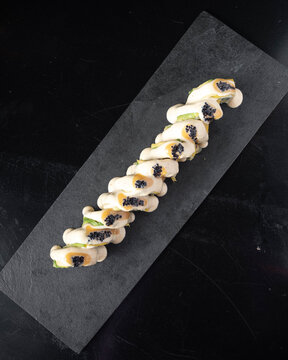 Elegant sushi roll rests on dark stone platter