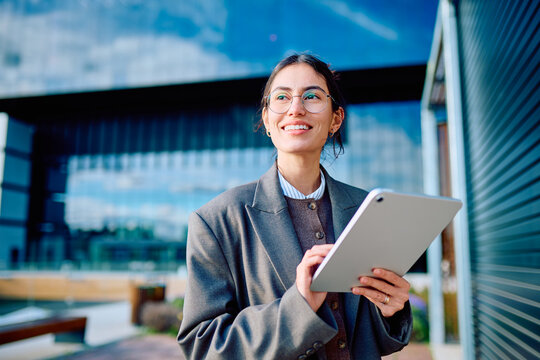 Young professional businesswoman smiling looking for future opportunities, working with technology in a modern urban environment