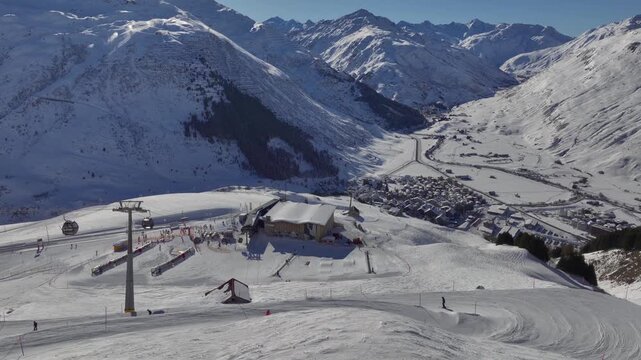 Andermatt Ski Resort in Switzerland. People Tourists riding skiing Snowboarding on snow-covered Slope, Aerial Drone View