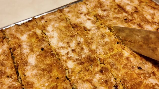 Freshly baked shortbread pie is cut into portions with a knife