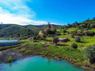 Fototapeta premium Serene rural landscape with a small cabin nestled on a green hillside overlooking a lake