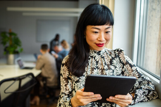 Professional woman using tablet by office window in coworking space