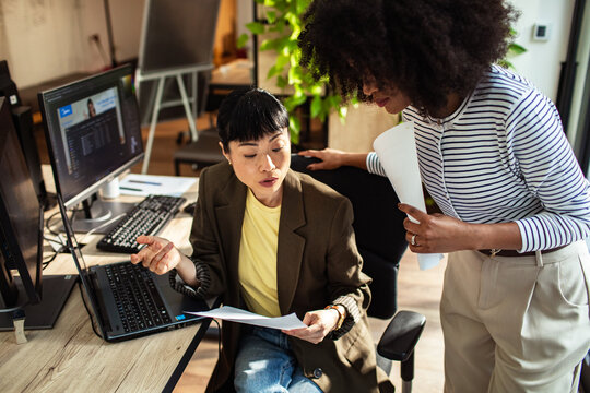 Two coworkers collaborating at computer in modern office