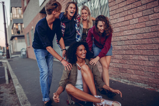 Group of friends laughing with skateboard on urban street