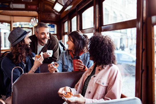 Friends sharing pastries and coffee on city tram