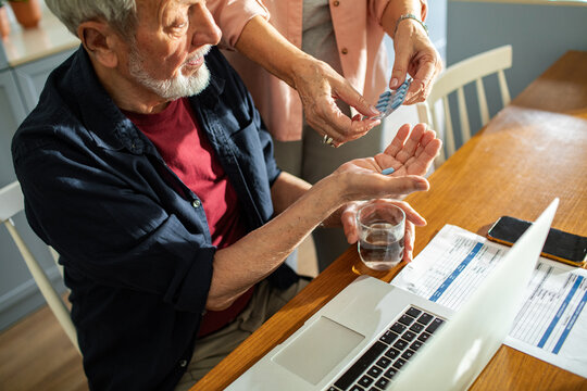 Senior man taking medication with caregiver at home