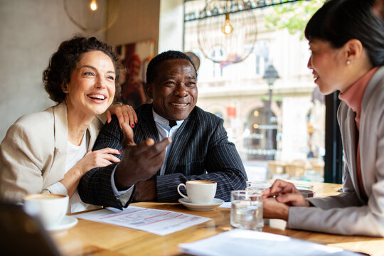 Happy couple consulting financial advisor at cafe
