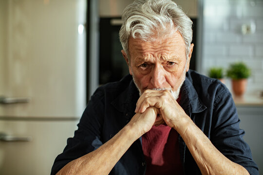 Worried senior man thinking at home kitchen