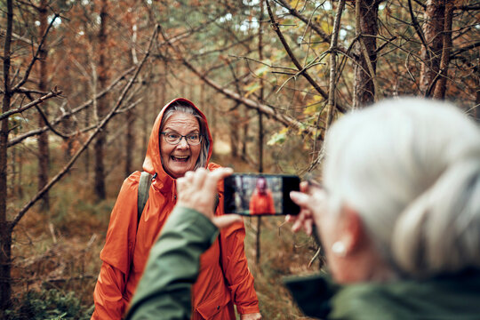Senior women taking smartphone photo on forest hike
