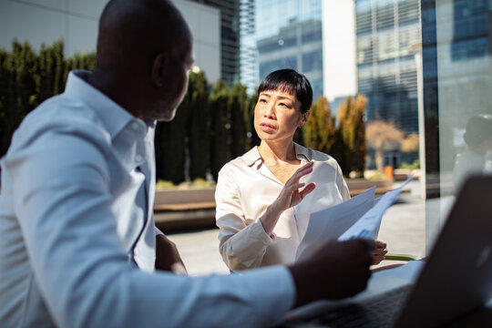 Two business colleagues discussing documents outside corporate office