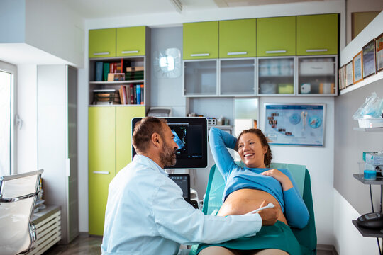 Obstetrician performing prenatal ultrasound on pregnant woman in clinic