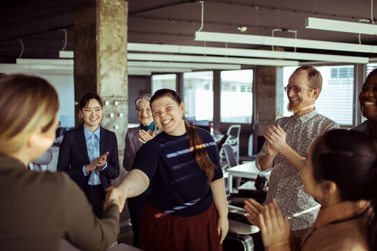 Coworkers applauding new team member in modern office
