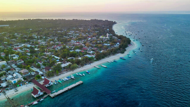 Aerial drone view of Gili Trawangan island at sunset showing golden sky, Mount Agung silhouette, and turquoise waters Indonesia