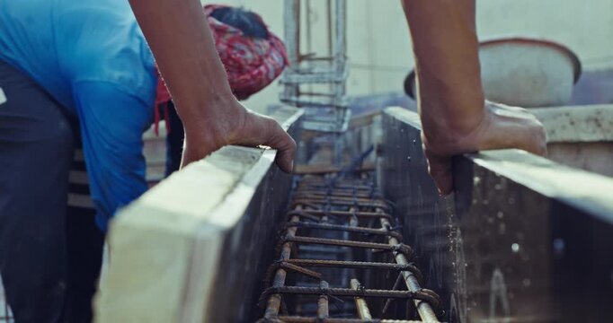 Construction workers tying steel rebar for beams and pillars, and hammering nails, capturing real on-site building process and structural work