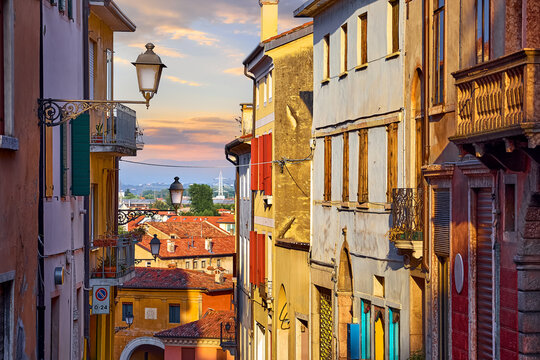 Bassano Del Grappa, Veneto Region, Italy. Street of old town with antique italian architecture and street lamps on the walls of houses. Sunset evening time.