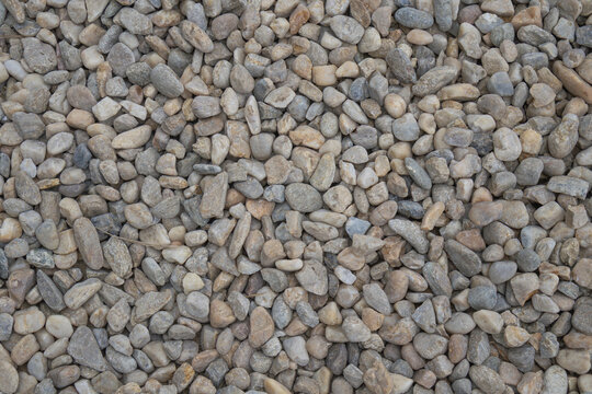 Top down view of a dense bed of smooth multi colored river pebbles and small gravel stones