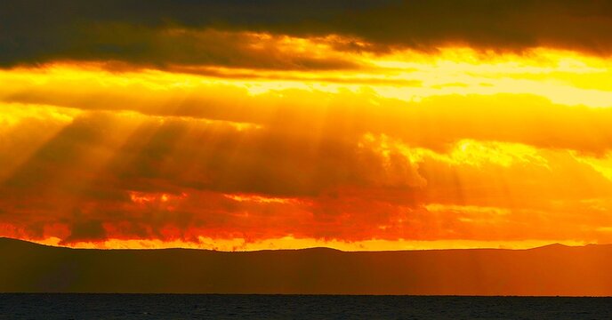 Burning sky with dramatic clouds and divine rays of light above the sea horizon divine Croatia