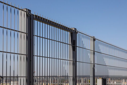 Industrial security and perimeter protection concept. Metal fence panels with rigid frame structure under clear sky, strong boundary system