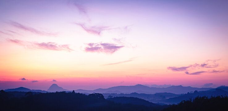 Panoramic sunrise over mountain ridge with vibrant purple and pink pastel sky, inspirational nature background and sky replacement banner