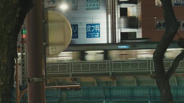 Cinematic motion blur of a fast commuter train passing through an urban street at dusk in Japan.
