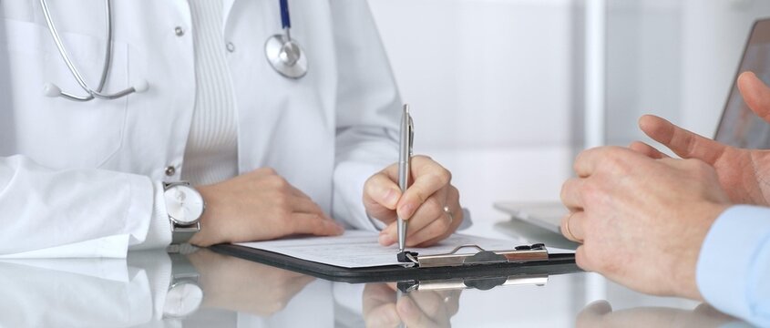 Doctor consulting patient, discussing medical history or treatment plan in modern clinic office, healthcare appointment. Medicine, healthcare and science concept