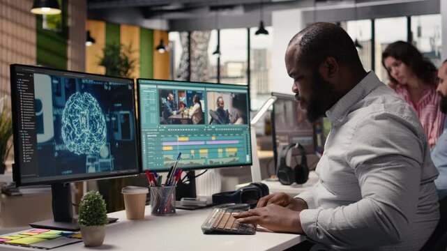 Black videographer refining footage with artificial intelligence tools in a high-tech post production agency. Editing software displays wireframe and data optimization powered by neural networks.