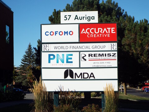 Nepean, Ontario, Canada &ndash; July 27, 2025: A multi-tenant monument sign at 57 Auriga Drive features "Cofomo, Accurate Creative, World Financial Group, PNE, Remisz, and MDA logos."