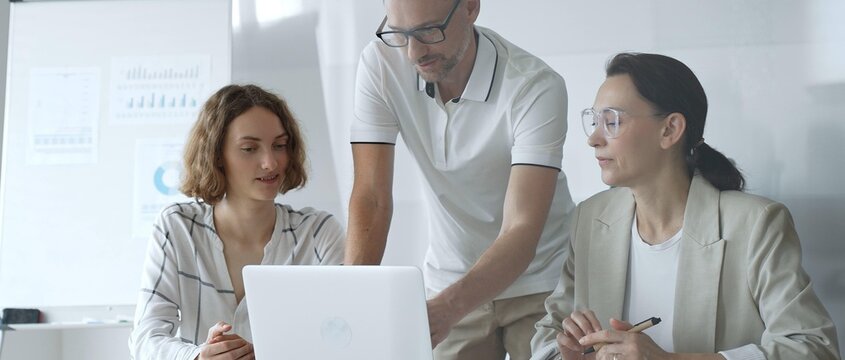 Business team collaborating and analyzing data on a laptop during a productive meeting in a modern office, fostering teamwork and strategic decision making