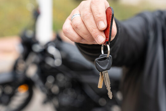 Hand holding motorcycle keys, showing new bike ownership, freedom, and an active biker lifestyle