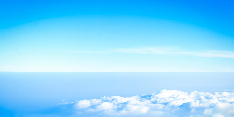 Obraz premium High angle view of clear blue sky with horizon and fluffy white clouds below.