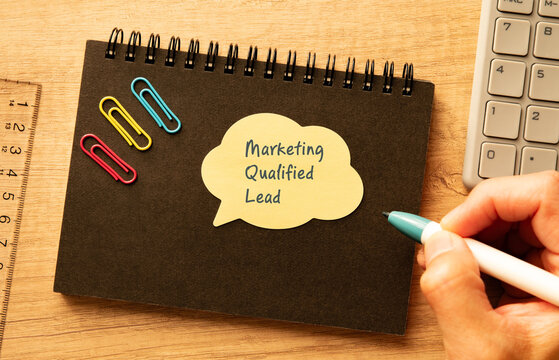 Business concept of Marketing Qualified Lead represented on speech bubble with calculator, pen, clips. Ideal for marketing and promotional content.