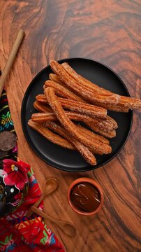 Typical churro dessert with artisanal chocolate and Mexican decorative elements. Camera rotating from an aerial view