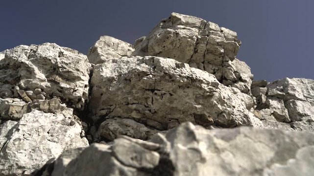 White gray limestone bedrock forms a stepped tectonic landscape with strong mineral relief. Pale calcite layers, rocky shelves, and uplifted ground create striking geologic texture outdoors.