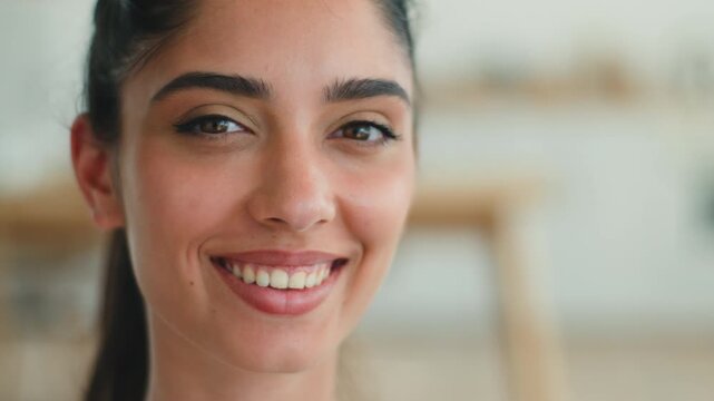 Pretty smiling Indian woman smile healthy teeth at home apartment relaxed look away thinking positive mood loan mortgage credit attractive Arabian female girl dental health looking at camera indoors