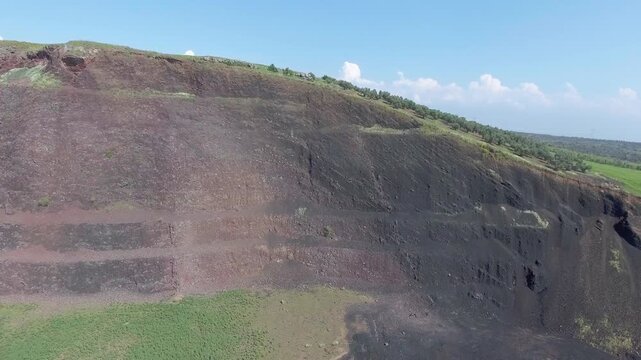 Aerial volcanic tuff cone layers reveal exposed mineral bands and rugged geologic structure. Eroded ash deposits, raw stratification, ancient eruption traces show striking earth history.