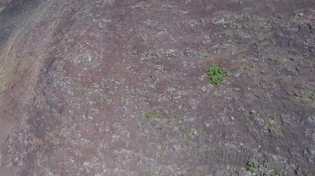 Aerial volcanic tuff cone layers reveal exposed mineral bands and rugged geologic structure. Eroded ash deposits, raw stratification, ancient eruption traces show striking earth history.