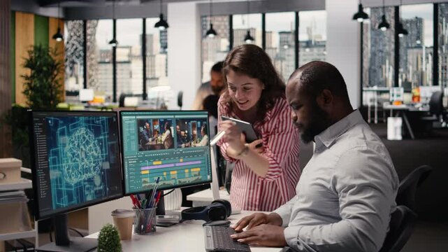 Creative team editing film footage with artificial intelligence software, transforming raw recorded clips into montage. Dual monitors show optimization tools powered by machine learning.