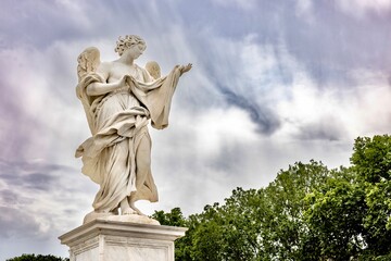 Fototapeta premium Angel statue on pedestal with dramatic cloudy sky in Rome