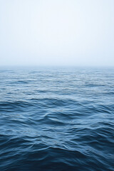 Fototapeta premium Calm Blue Ocean Surface Meets Hazy Sky Horizon in Fog