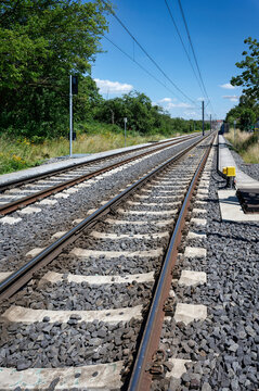 Low angle view of double railway tracks disappearing into the distance. Clean, modern infrastructure in Cologne, Germany, on a sunny summer day.