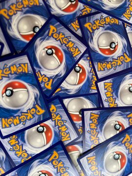 Bekasi, Indonesia - March 04, 2026: A vertical close-up of several scattered Pok&eacute;mon Trading Card Game (TCG) cards, featuring the classic blue back design with the iconic Pok&eacute; Ball and yellow logo.