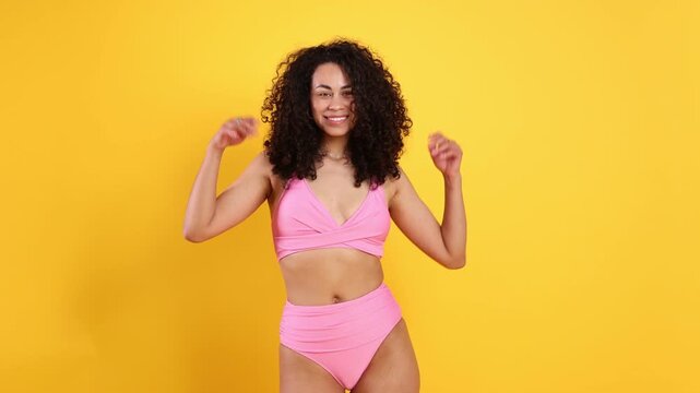 Beautiful woman wearing pink swimsuit on orange background