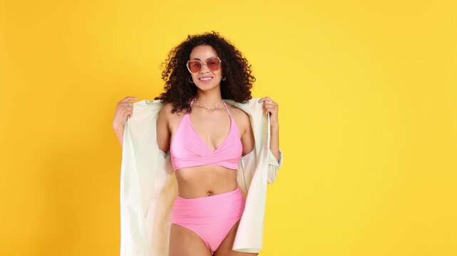 Beautiful woman wearing pink swimsuit and shirt on orange background