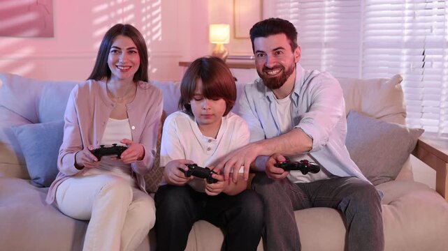 Happy family playing video game together on sofa at home