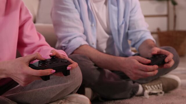Father and daughter with controllers playing video game at home, closeup. Camera moving forward and backwards